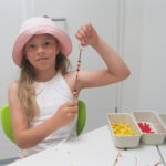 In der Schmuckwerkstatt zeigt Milana den Schlüsselanhänger in Deutschland-Farben, den sie gerade herstellt. Foto: Schule